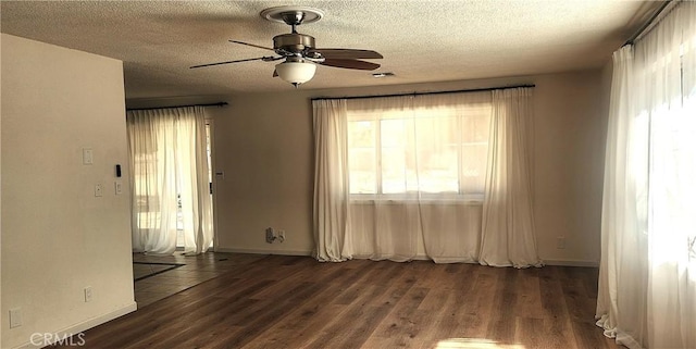 spare room with ceiling fan, a textured ceiling, baseboards, and wood finished floors