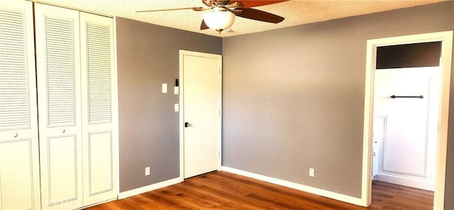 unfurnished bedroom with a textured ceiling, a closet, wood finished floors, and baseboards