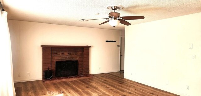 unfurnished living room featuring a textured ceiling, a fireplace, a ceiling fan, and wood finished floors