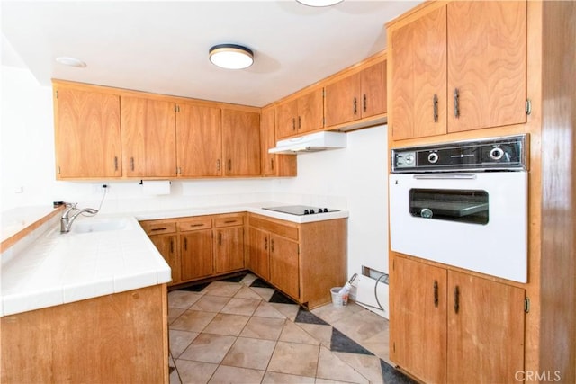 57825 El Dorado Dr, Yucca Valley, CA 92284 - kitchen with white oven, under cabinet range hood, black electric stovetop, tile countertops, and light tile patterned floors