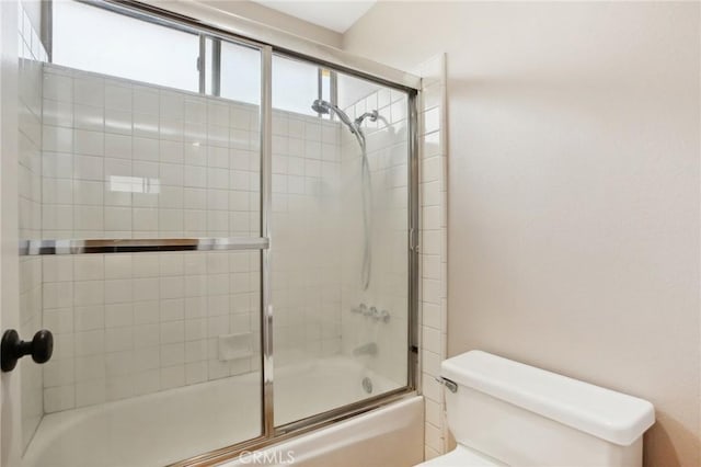 bathroom featuring enclosed tub / shower combo and toilet