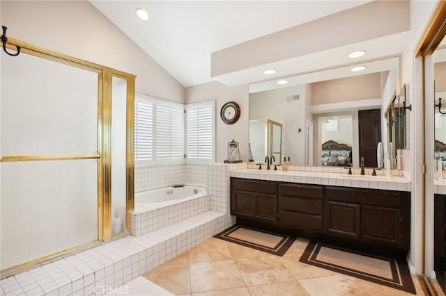 bathroom featuring tile patterned floors, vanity, a relaxing tiled tub, and vaulted ceiling