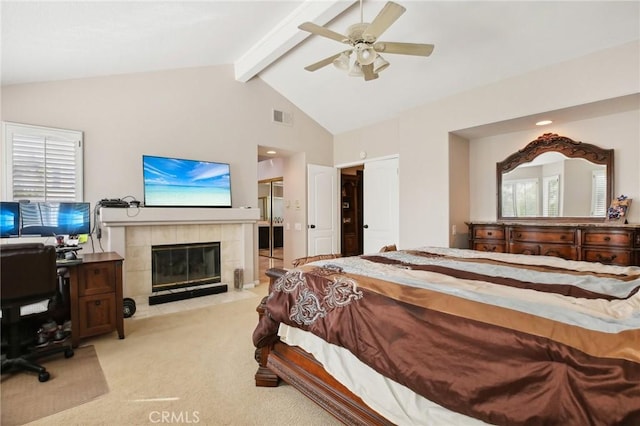 bedroom featuring light carpet, high vaulted ceiling, a tile fireplace, ceiling fan, and beamed ceiling