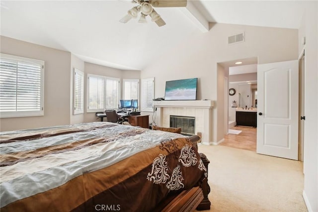 carpeted bedroom with a tile fireplace, lofted ceiling with beams, ensuite bath, and ceiling fan