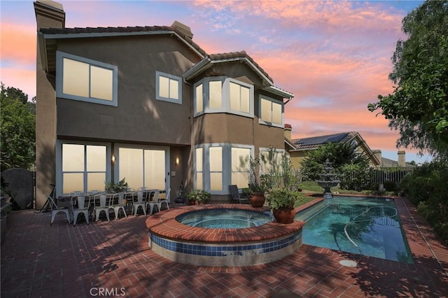 back house at dusk with a patio area and a fenced in pool