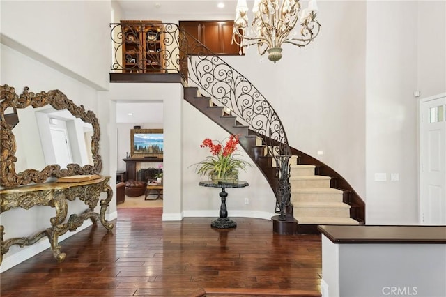 foyer entrance featuring hardwood / wood-style floors, a towering ceiling, plenty of natural light, and a notable chandelier