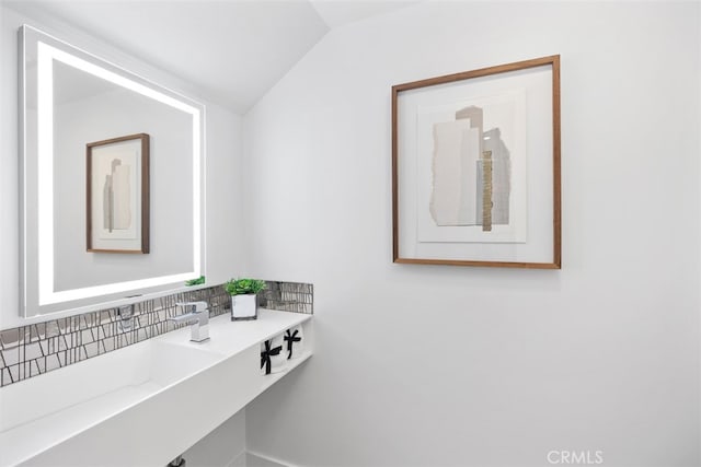 bathroom with lofted ceiling and tasteful backsplash