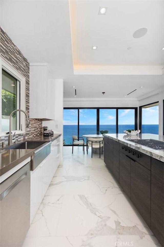 kitchen featuring a healthy amount of sunlight, a water view, and white cabinetry