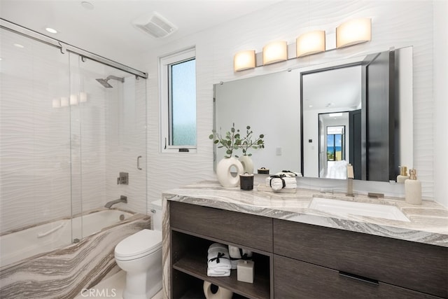 full bathroom featuring combined bath / shower with glass door, vanity, and toilet