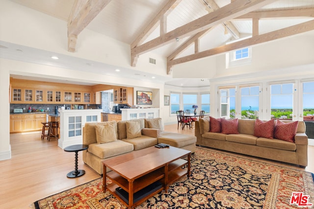 living room with a water view, high vaulted ceiling, beamed ceiling, light wood-type flooring, and french doors