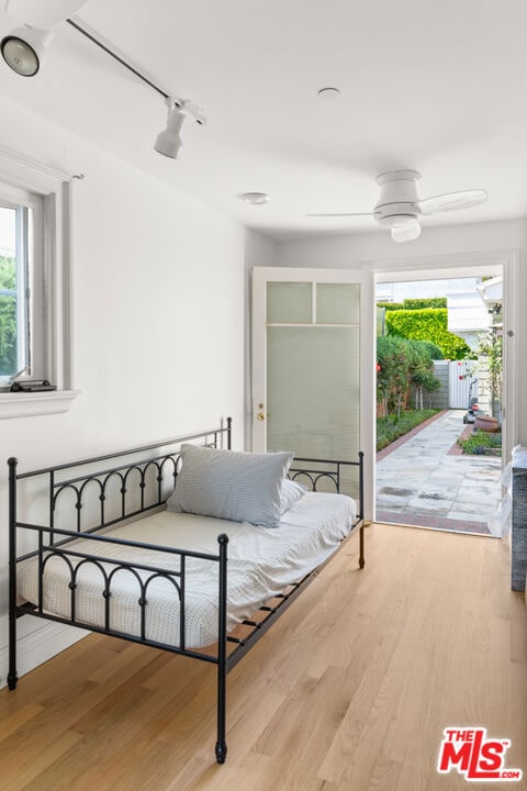 bedroom with ceiling fan, multiple windows, access to exterior, and hardwood / wood-style floors