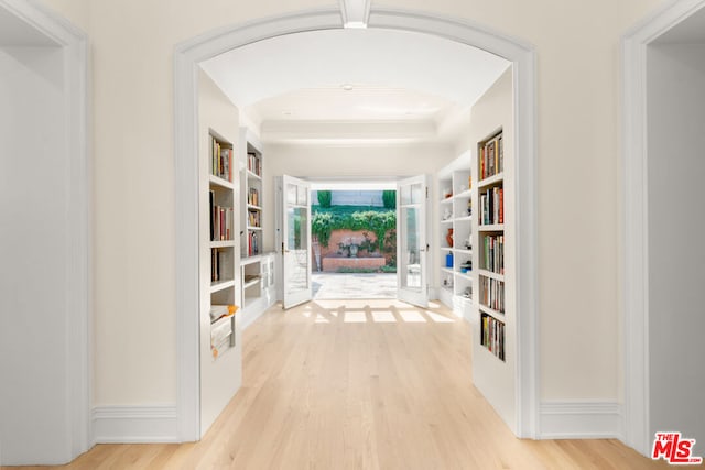 corridor with a tray ceiling and light hardwood / wood-style floors