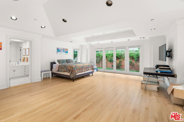 bedroom featuring light wood-type flooring, crown molding, a tray ceiling, and ensuite bathroom