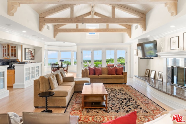 living room with light hardwood / wood-style flooring, a premium fireplace, high vaulted ceiling, and a wealth of natural light