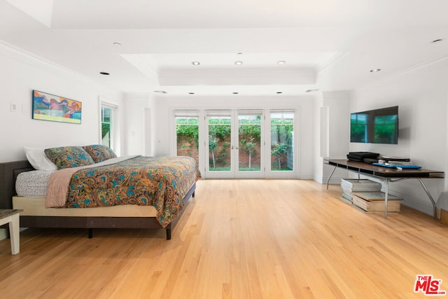 bedroom with wood-type flooring, a raised ceiling, french doors, and crown molding