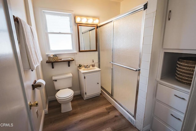 bathroom with tasteful backsplash, vanity, a shower with door, wood-type flooring, and toilet