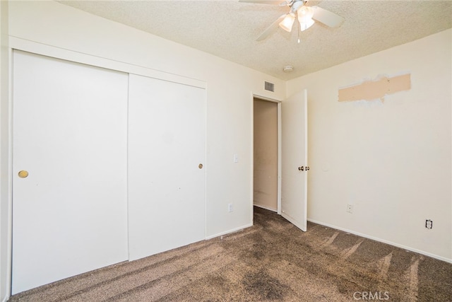 unfurnished bedroom featuring ceiling fan, dark carpet, a closet, and a textured ceiling