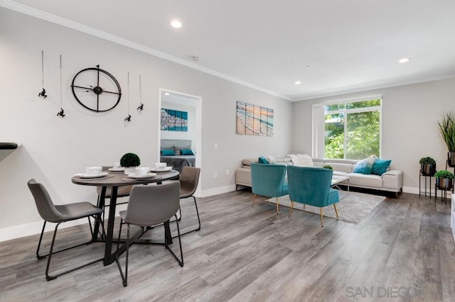 dining area with light wood-type flooring and ornamental molding