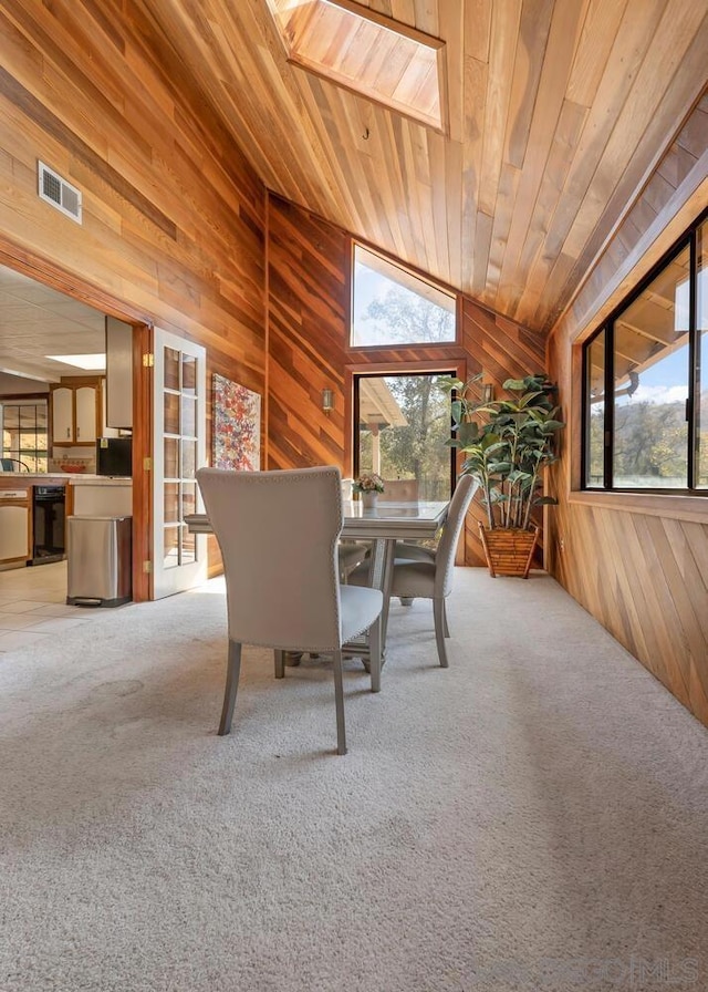 unfurnished dining area featuring lofted ceiling with skylight, wood walls, and plenty of natural light