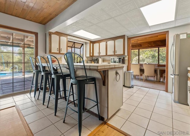 kitchen featuring stainless steel appliances, light tile patterned floors, a kitchen bar, and a wealth of natural light