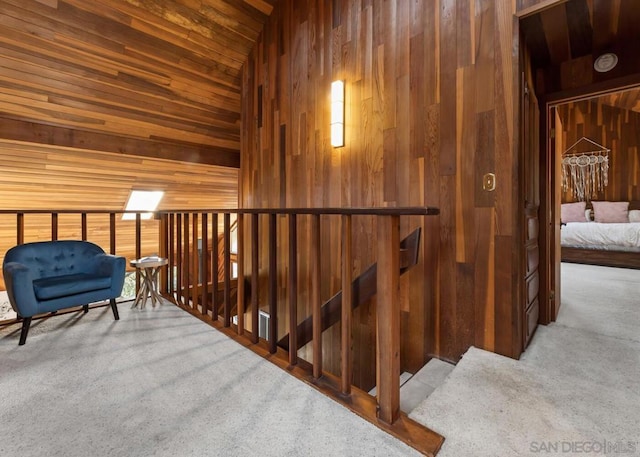 hallway featuring light colored carpet, wooden ceiling, and wood walls