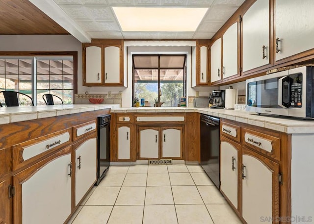 kitchen featuring sink, light tile patterned floors, dishwasher, and tile countertops