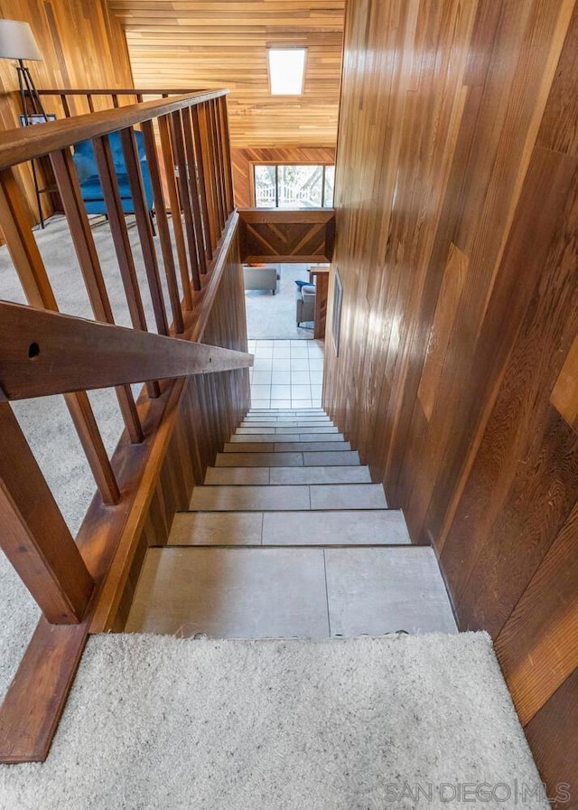 staircase featuring tile patterned floors and wood walls