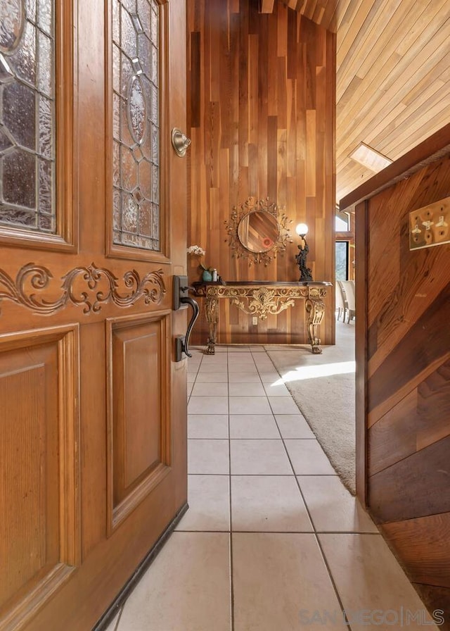 corridor featuring vaulted ceiling, wood walls, wooden ceiling, and light tile patterned flooring