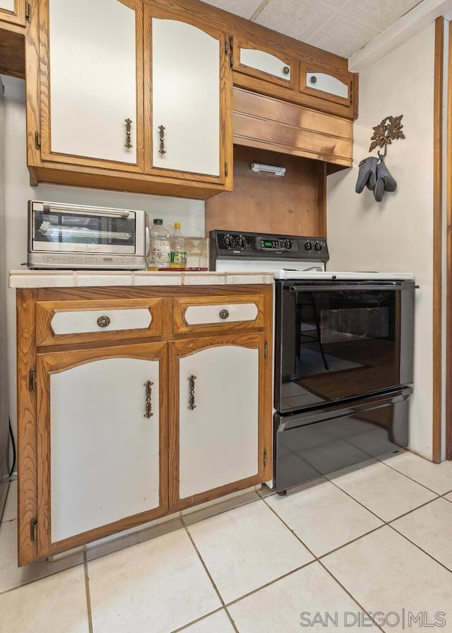 kitchen with premium range hood, range with electric cooktop, and light tile patterned floors