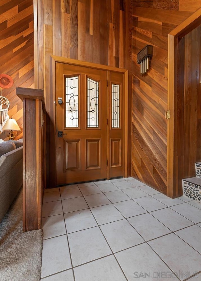 tiled foyer entrance featuring wood walls