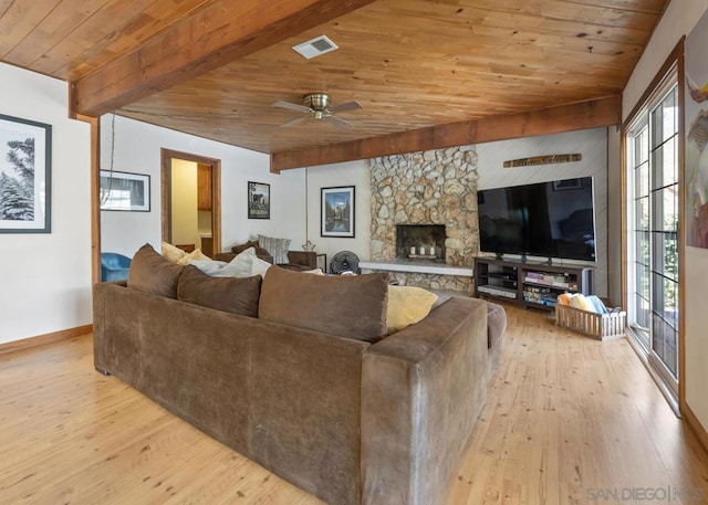 living room with a stone fireplace, ceiling fan, wooden ceiling, beamed ceiling, and light hardwood / wood-style flooring