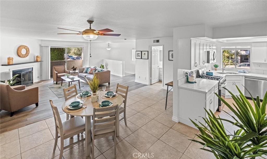 dining area with a textured ceiling, light hardwood / wood-style floors, and ceiling fan