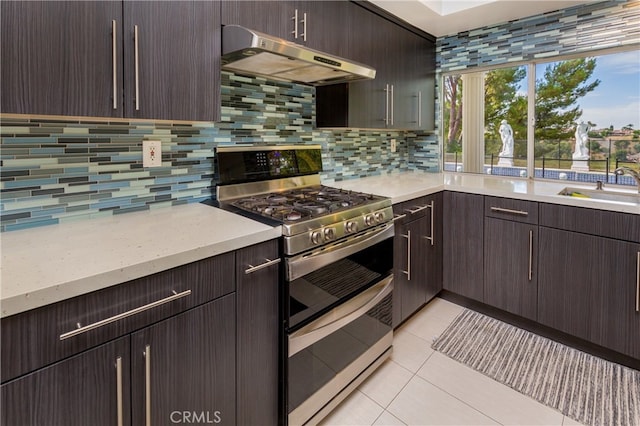 kitchen featuring sink, range with two ovens, backsplash, exhaust hood, and light tile patterned floors