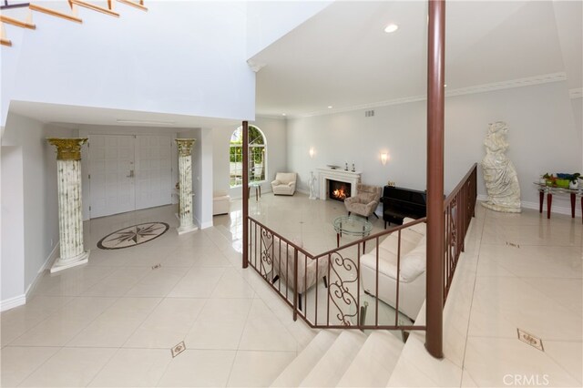 tiled entrance foyer featuring crown molding and ornate columns