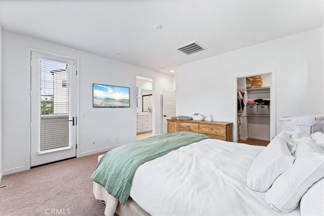 carpeted bedroom featuring a closet, a walk in closet, and ensuite bath