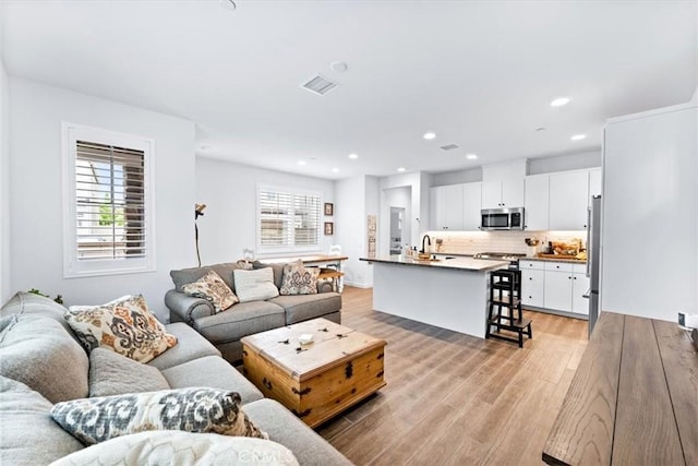 living room featuring light wood-type flooring and sink