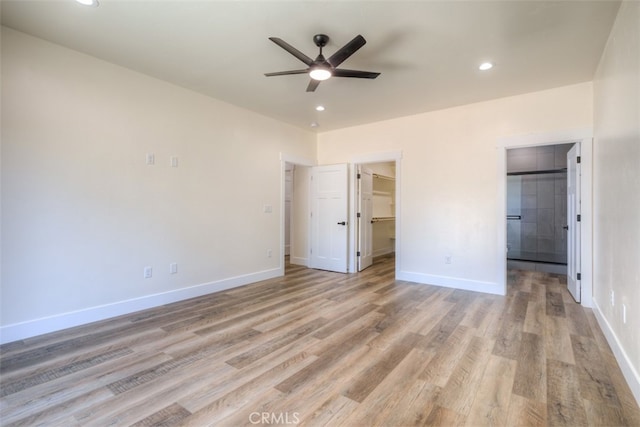 unfurnished bedroom featuring light hardwood / wood-style floors, a walk in closet, and ceiling fan