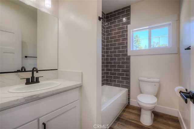 full bathroom featuring wood-type flooring, vanity, tiled shower / bath combo, and toilet