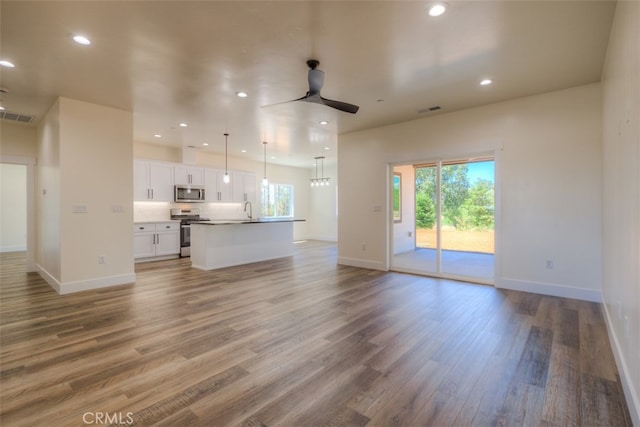 unfurnished living room featuring ceiling fan, hardwood / wood-style floors, and sink