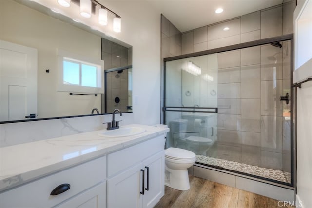 bathroom with walk in shower, hardwood / wood-style flooring, vanity, and toilet