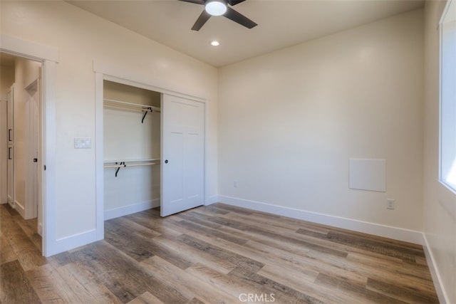 unfurnished bedroom with ceiling fan, a closet, and wood-type flooring