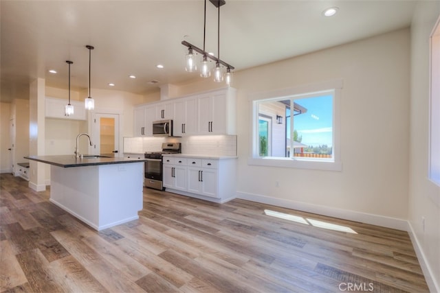 kitchen with hanging light fixtures, light hardwood / wood-style floors, white cabinetry, and stainless steel appliances