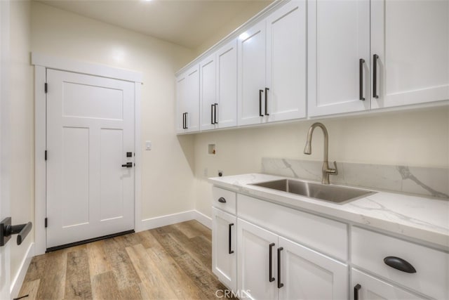 clothes washing area with cabinets, hookup for an electric dryer, light hardwood / wood-style floors, sink, and hookup for a washing machine