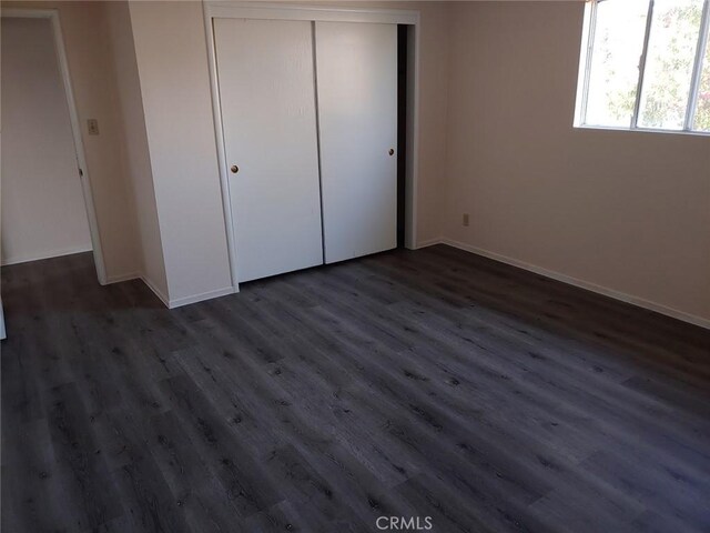 unfurnished bedroom featuring dark wood-type flooring and a closet