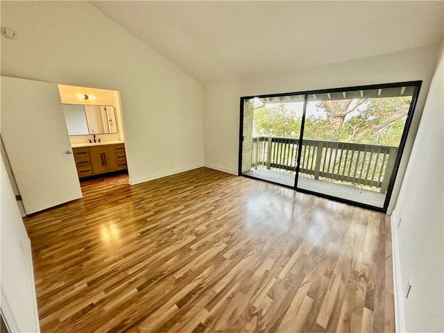 unfurnished bedroom featuring access to outside, light hardwood / wood-style floors, vaulted ceiling, and ensuite bath