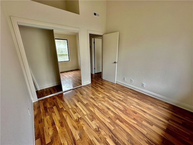 unfurnished bedroom featuring light hardwood / wood-style floors and a towering ceiling