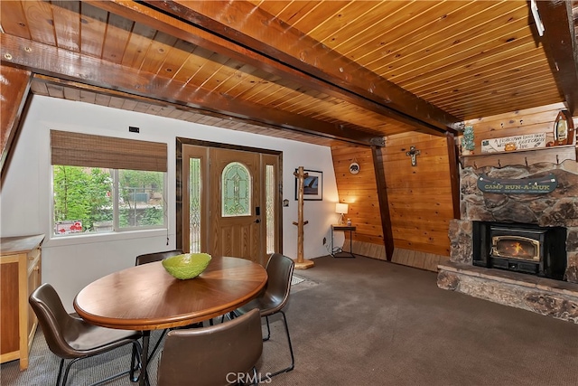 carpeted dining area with beamed ceiling, wooden walls, and wooden ceiling