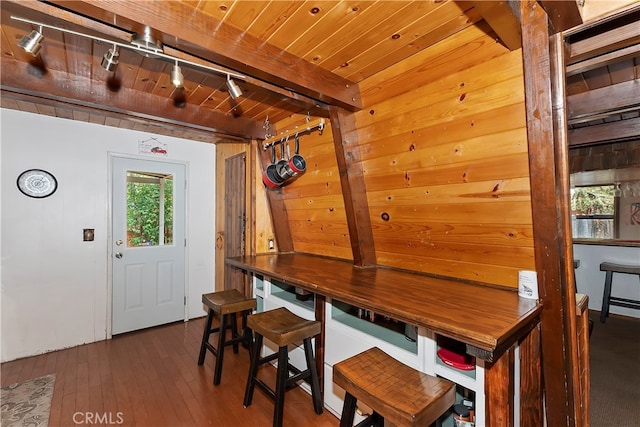 dining area with dark wood-type flooring, beam ceiling, wooden ceiling, and track lighting