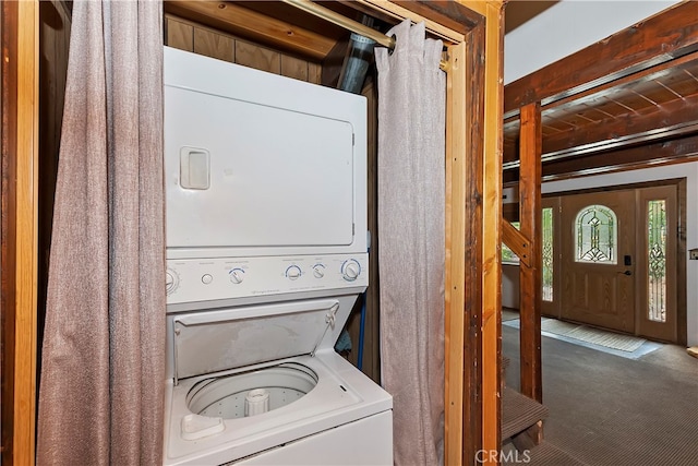 clothes washing area featuring stacked washer / dryer and carpet floors