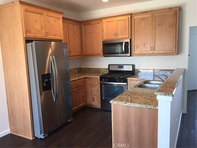 kitchen featuring appliances with stainless steel finishes, kitchen peninsula, light stone countertops, dark hardwood / wood-style flooring, and sink